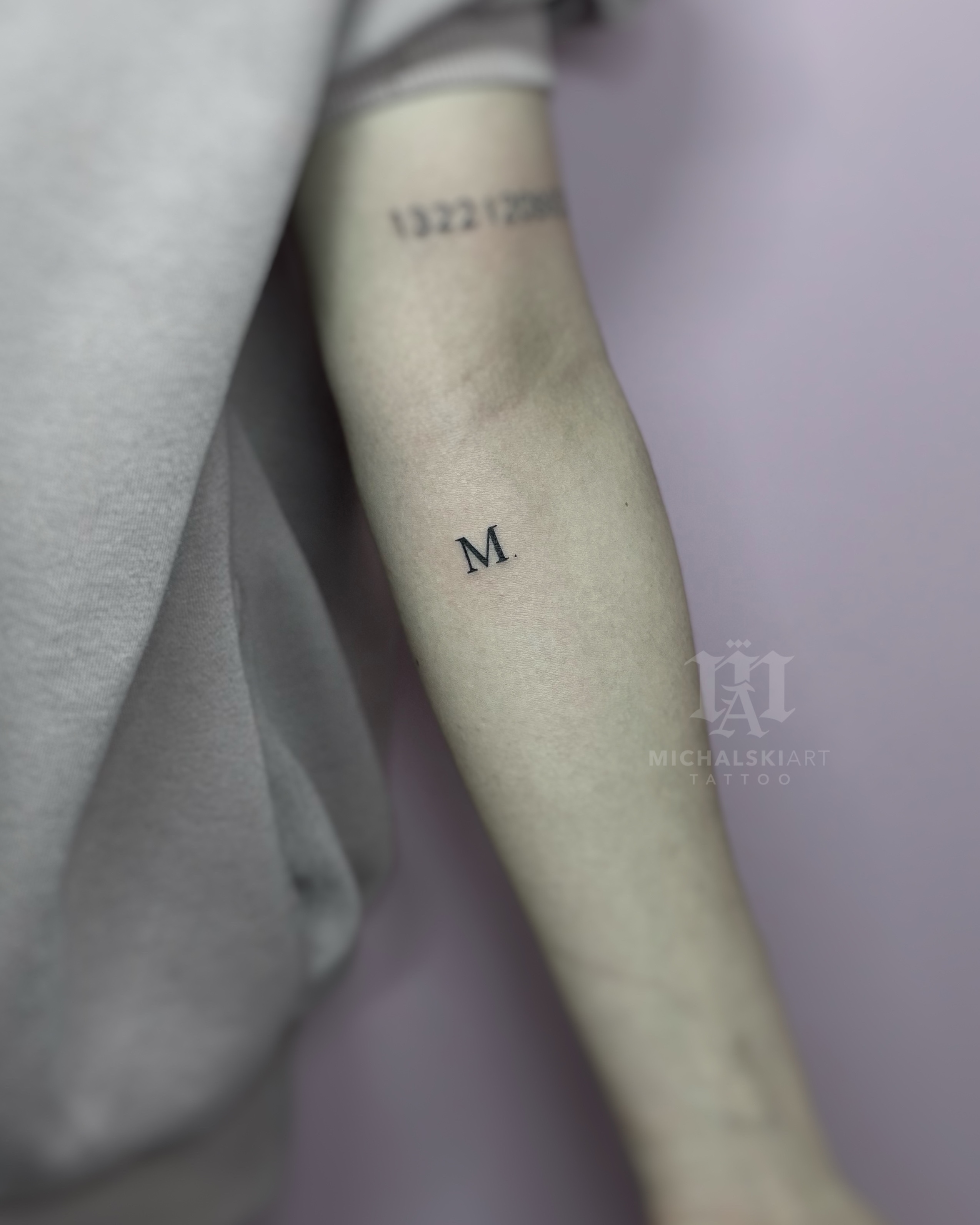 minimalistyczny tatuaż litera M